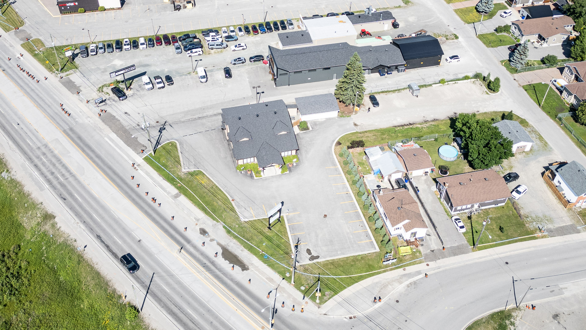 High aerial view of the full property showing its corner-lot road frontage and on-site parking